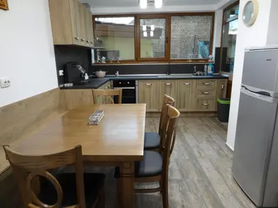 a kitchen with a wooden table and a refrigerator at Къща за гости Мегдана in Sopot