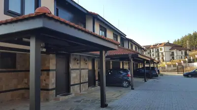 a car parked in a parking lot next to a building at Къщи за гости КООП Добринище - Holiday Villages COOP Dobrinishte in Dobrinishte