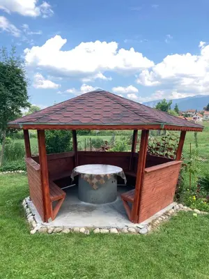 a wooden gazebo with a table in the grass at Atanasovata Kashta in Govedartsi