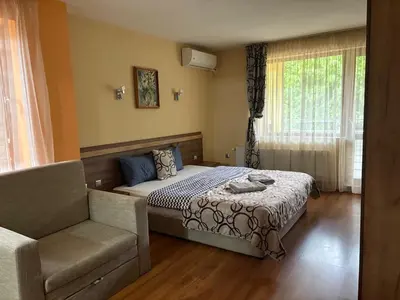 a bedroom with a bed and a couch and a chair at Kot Garden Guest House in Sapareva Banya