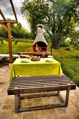 a picnic table with a fireplace in a backyard at Holiday Home Marta in Dobrevtsi