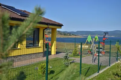 a fence in front of a house next to the water at Guest House Colori in Tsigov Chark