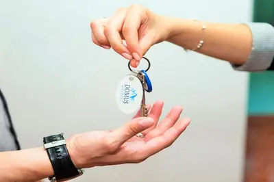 a person holding up a pair of keys at Domus Apartments City Center with Parking in Plovdiv