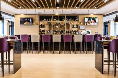 a restaurant with purple chairs and a bar at Premier Sofia Airport Hotel in Sofia