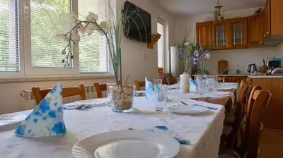 a dining room table with white plates and flowers on it at Pamir Guest House in Shipkovo