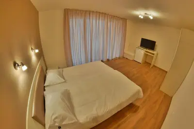 a bedroom with a white bed and a television at Villa Pirin in Simitli