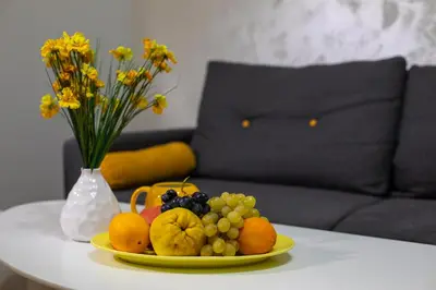 a plate of fruit on a table with a vase of flowers at Old Town Apartment in Plovdiv