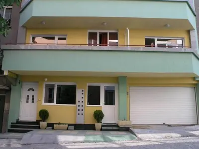 a yellow and white house with two garage doors at Hotel Ertancom in Blagoevgrad