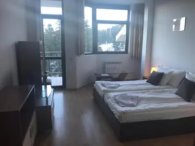 a bedroom with a large bed and two windows at Flora Apartment 619 in Borovets