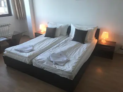 a bed with white sheets and pillows and two lamps at Flora Apartment 619 in Borovets
