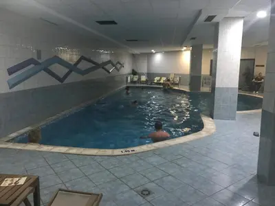 a pool in a hotel with people in the water at Flora Apartment 619 in Borovets