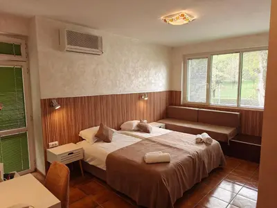 a bedroom with a bed and a couch and two windows at Noviz Hotel in Plovdiv