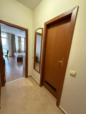 a hallway with a wooden door and a mirror at PM Services Flora Apartments in Borovets