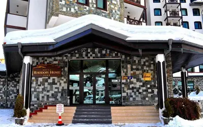 a building with snow on top of it at Rhodopi Home Hotel Chepelare- Half Board & Wellness in Chepelare
