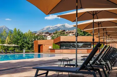 a group of chairs with umbrellas next to a pool at Four Points by Sheraton Bansko in Bansko