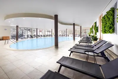 a pool with a row of chairs in a building at Four Points by Sheraton Bansko in Bansko