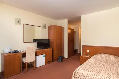 a hotel room with a bed and a desk with a television at Hotel Pirin SKI & SPA in Bansko