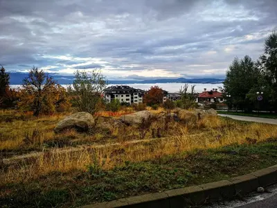 a field of grass with some rocks and a building at Royal Bansko Family Apart Hotel - All Inclusive Light or Half Board & Drinks With Heated Indoor Pool & Jacuzzis in Bansko