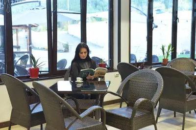 a woman sitting at a table reading a book at Royal Bansko Family Apart Hotel - All Inclusive Light or Half Board & Drinks With Heated Indoor Pool & Jacuzzis in Bansko