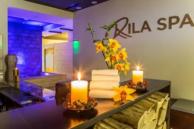 a table with two candles and a vase of flowers at Rila Hotel Borovets in Borovets