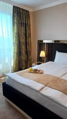 a large bed in a hotel room with a large window at Astoria Grand Hotel in Sofia