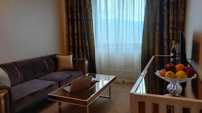 a living room with a couch and a table with a bowl of fruit at Astoria Grand Hotel in Sofia