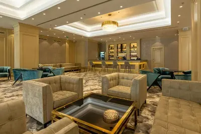 a lobby with chairs and a bar in the background at Astoria Grand Hotel in Sofia