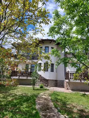 a large white building with a balcony and trees at Pinerose Resort in Bansko
