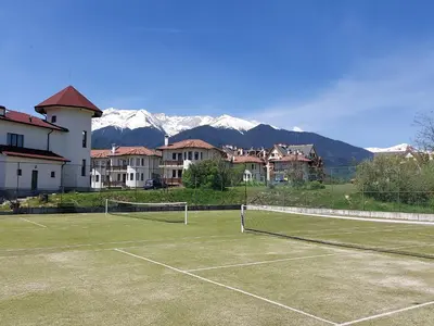a tennis court with mountains in the background at Pinerose Resort in Bansko