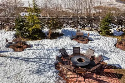 a snow covered yard with chairs and a bridge at MPM Hotel Sport Ski-in, Ski-out in Bansko