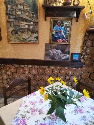 a table with a vase of flowers and pictures on a wall at Family Hotel Santo Bansko in Bansko