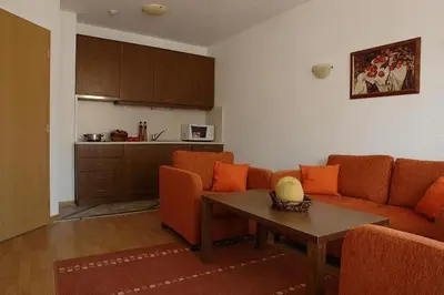 a living room with an orange couch and a table at Winslow Elegance Apartments in Bansko