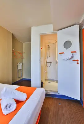 a bedroom with an orange bed and a shower at easyHotel Sofia in Sofia