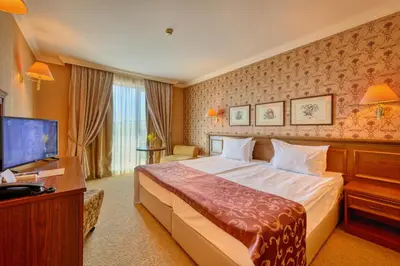 a hotel room with a bed and a flat screen tv at Hotel Club Central in Hisarya
