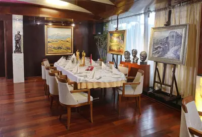 a dining room with a table and chairs and paintings at Hotel Anel in Sofia
