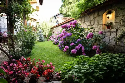 a garden with flowers and a stone wall at Lina Hotel in Bansko