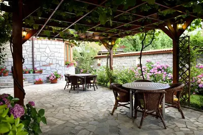 a patio with tables and chairs under a pergola at Lina Hotel in Bansko