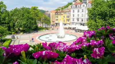 a fountain in the middle of a city with purple flowers at Guest House Fun and Rest in Plovdiv