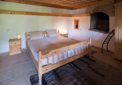 a bedroom with a large wooden bed in a room at Кюповата къща 1860 Qpova house in Kovachevitsa