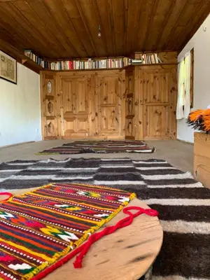 a room with a rug on the floor and wooden walls at Кюповата къща 1860 Qpova house in Kovachevitsa