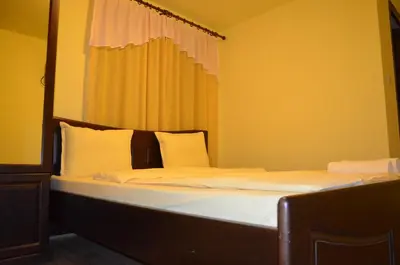 a bed with white sheets and pillows in a room at Guest House Ivan in Cherni Osŭm