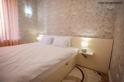 a small bedroom with a white bed with two lamps at Presidency House Self Check-in Apartments in Sofia