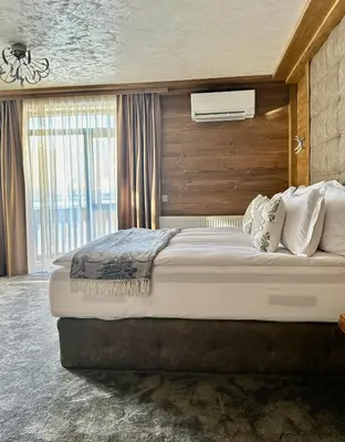 a bedroom with a large bed with a wooden wall at V Chalet Residence in Velingrad