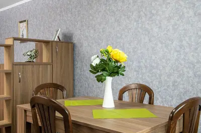 a dining room table with a vase of yellow flowers at Panorama Apartment in Velingrad