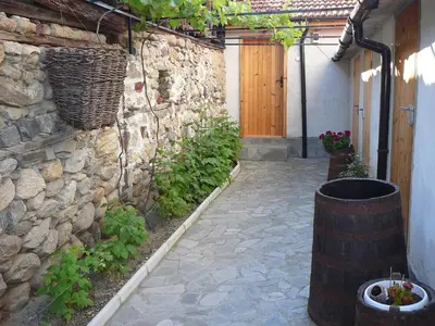 a courtyard with a stone wall and a barrel at Guesthouse Argacho in Stob