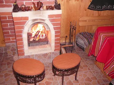 a fireplace with two stools in front of it at Guesthouse Argacho in Stob