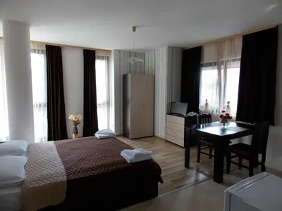 a hotel room with a bed and a desk and a table at Apart Hotel Rosen in Sofia
