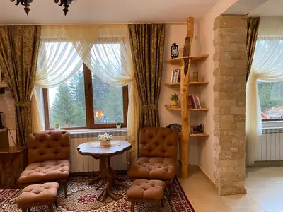 a living room with two chairs and a table and windows at Villa Hills - къща за гости с храна in Orlino