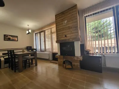 a living room with a table and a fireplace at Ваканционна къща ,,Родопски уют 