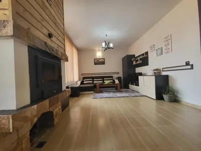 a living room with a fireplace and a table at Ваканционна къща ,,Родопски уют 